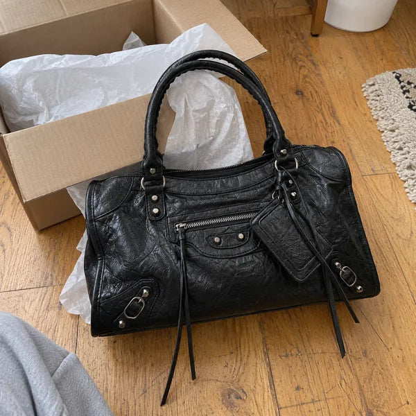 Immagine generata con IA: borsa It Girl media, nera, in un contesto quotidiano