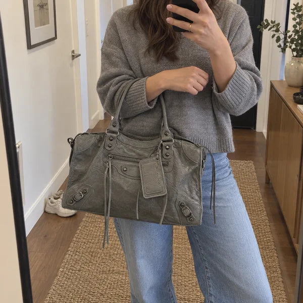 Immagine generata con IA: borsa It Girl media, grigio scuro, in un contesto quotidiano