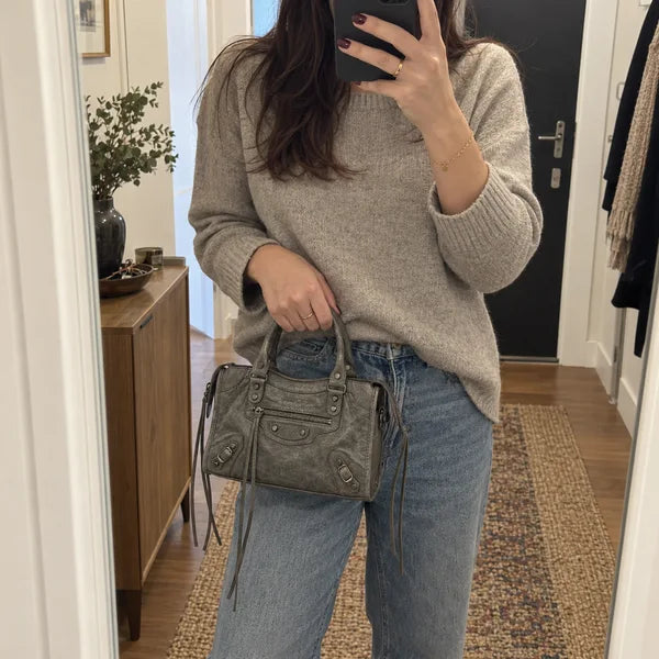 Immagine generata con IA: borsa It Girl piccola, grigio scuro, in un contesto quotidiano